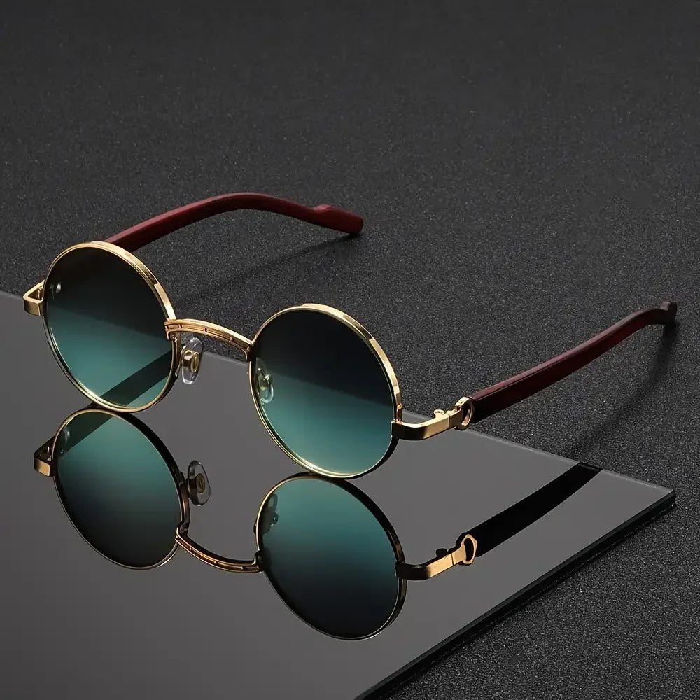 Round sunglasses with gold frame and green lenses on a dark surface