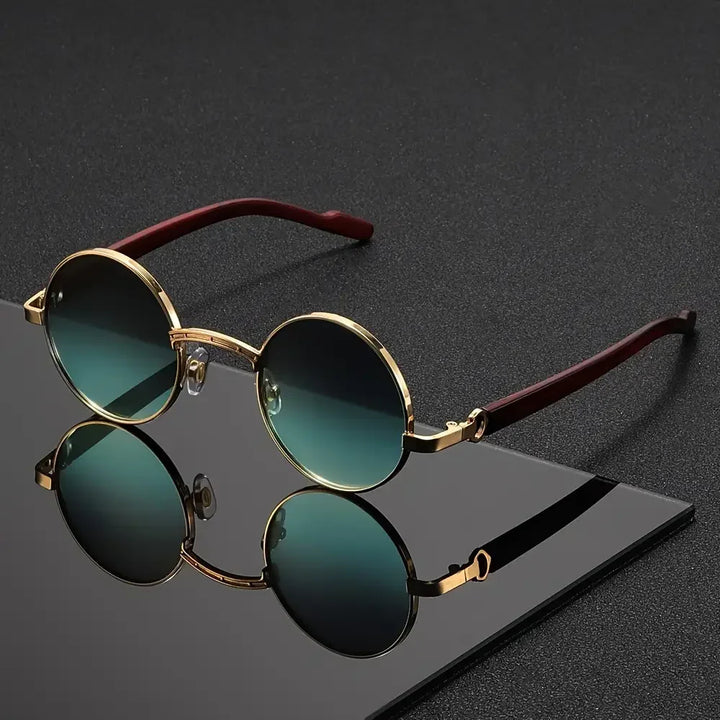 Round sunglasses with gold frame and green lenses on a dark surface
