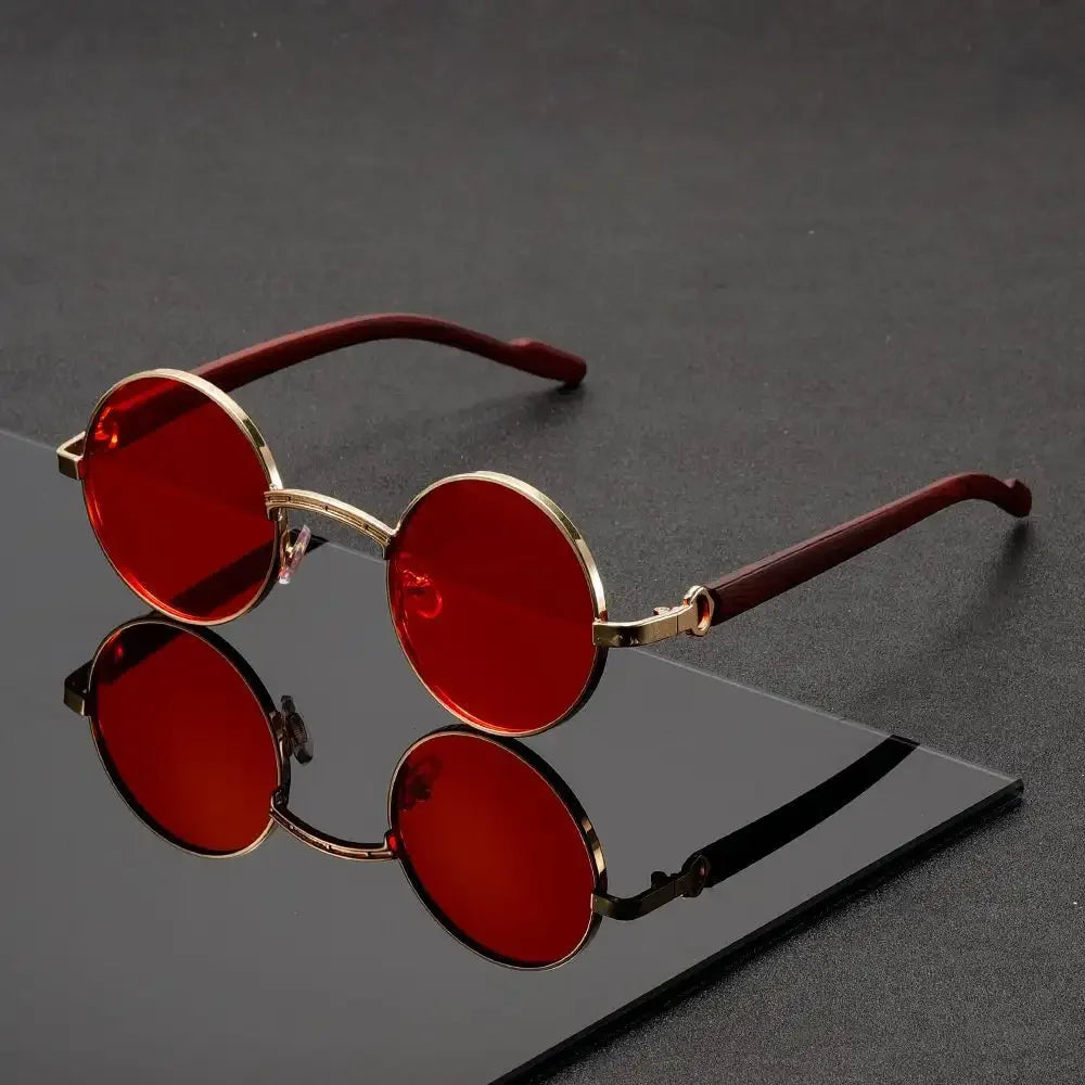 Red sunglasses with gold frames on a reflective black surface