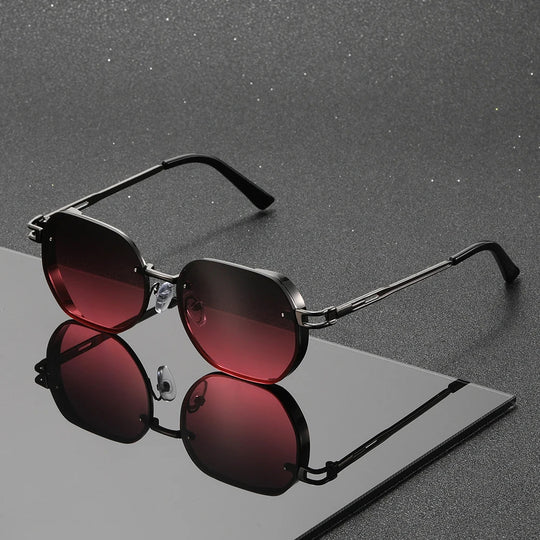 Sunglasses with red lenses and black frames on a reflective surface with a gray background
