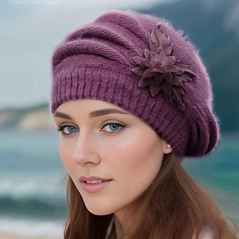 Woman wearing a purple knit hat with a flower on a blurred natural background