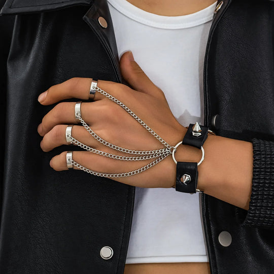 Close-up of a person wearing multiple silver chains and a black bracelet on a black jacket background